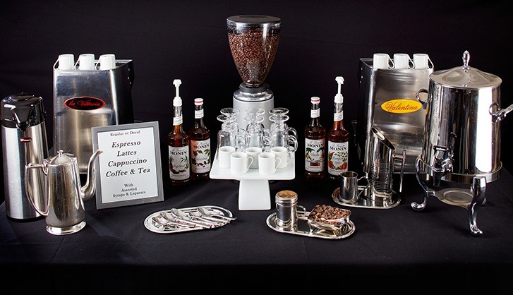Coffee beverage station showcasing espresso, lattes, cappuccinos, and tea with equipment, flavored syrups, and service accessories for events.